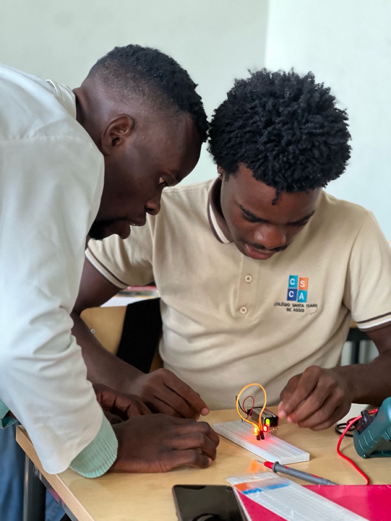 Dois alunos do CSCA concentrados a testar um circuito com LEDs numa breadboard