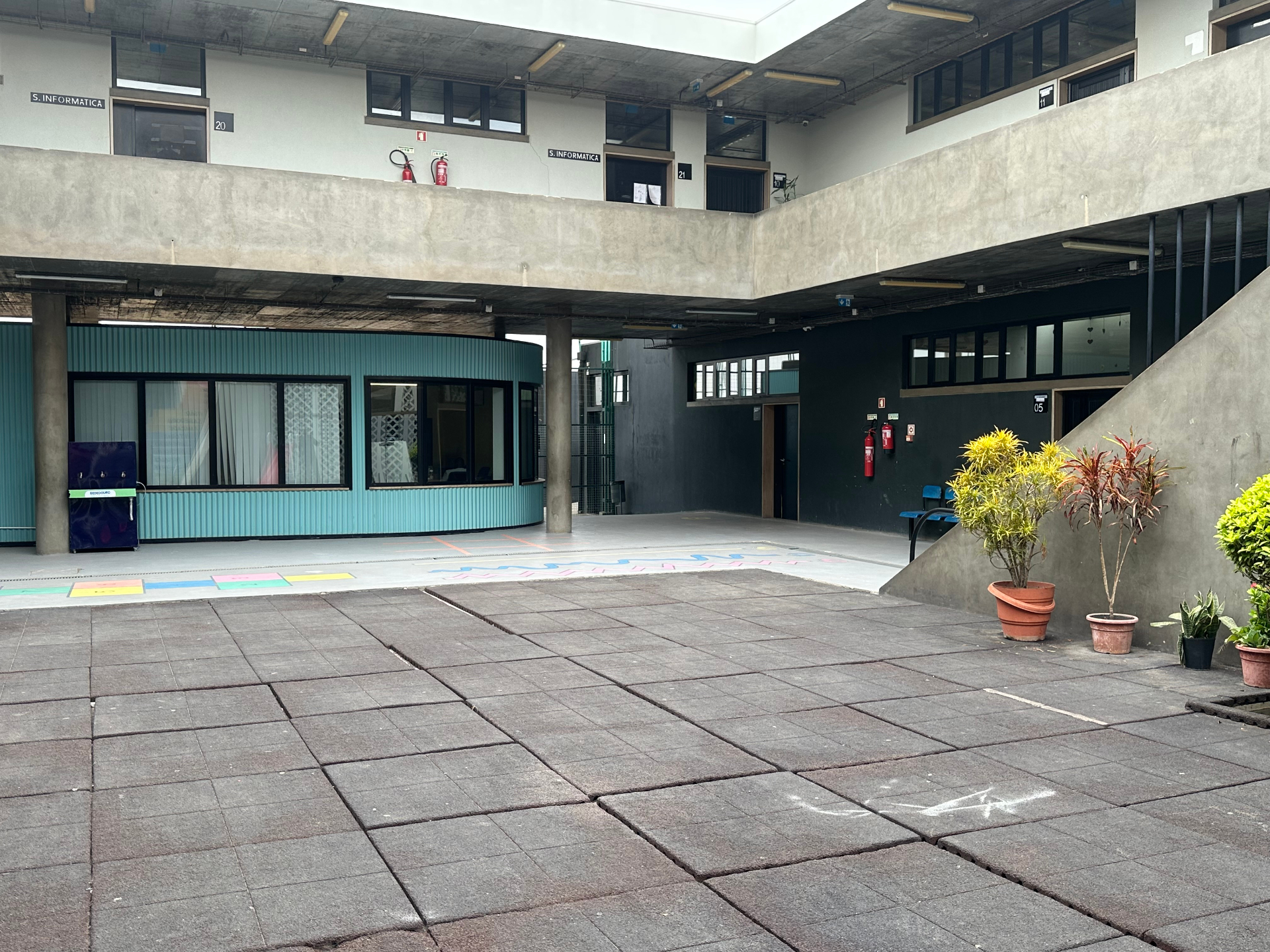 Pátio interior do Colégio Santa Clara de Assis com pintura pedagógica no chão e Salas de Informática ao fundo